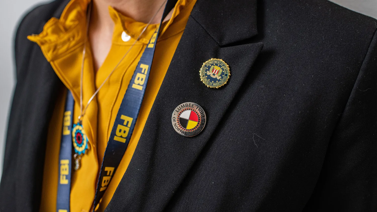 Two FBI pins attached to the flap of a women’s blazer