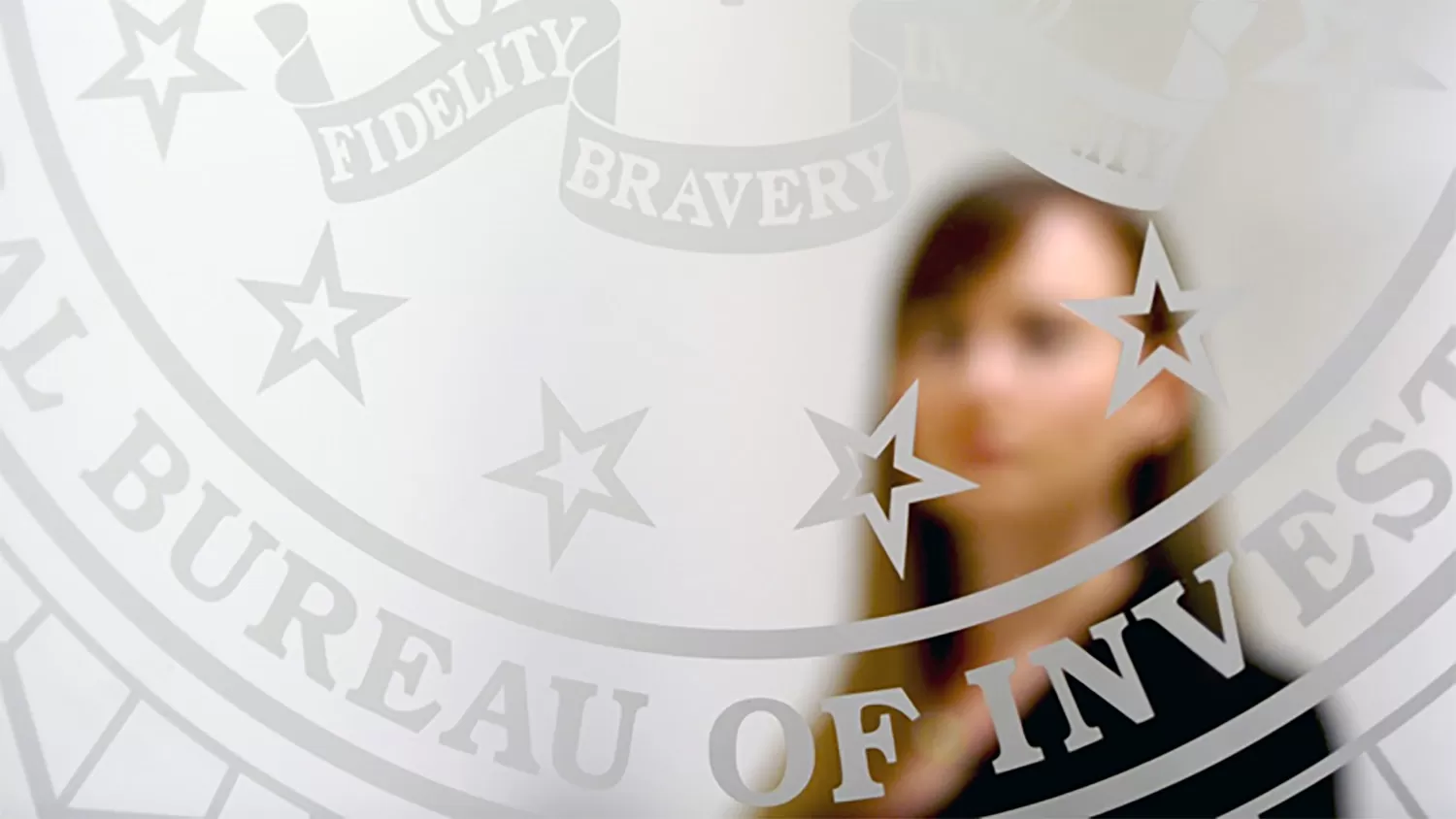 Female FBI employee standing behind a glass door with FBI Seal printed on it