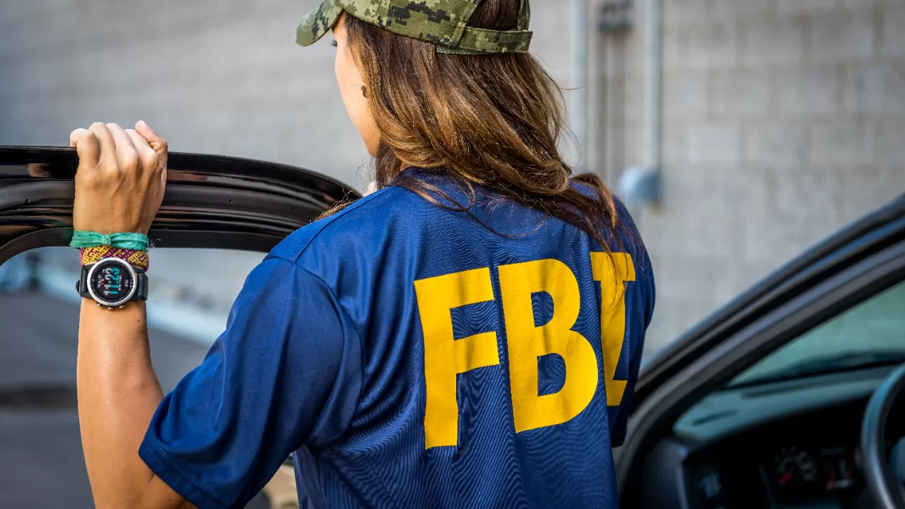 Female agent with FBI t-shirt on standing outside of the car with back turned