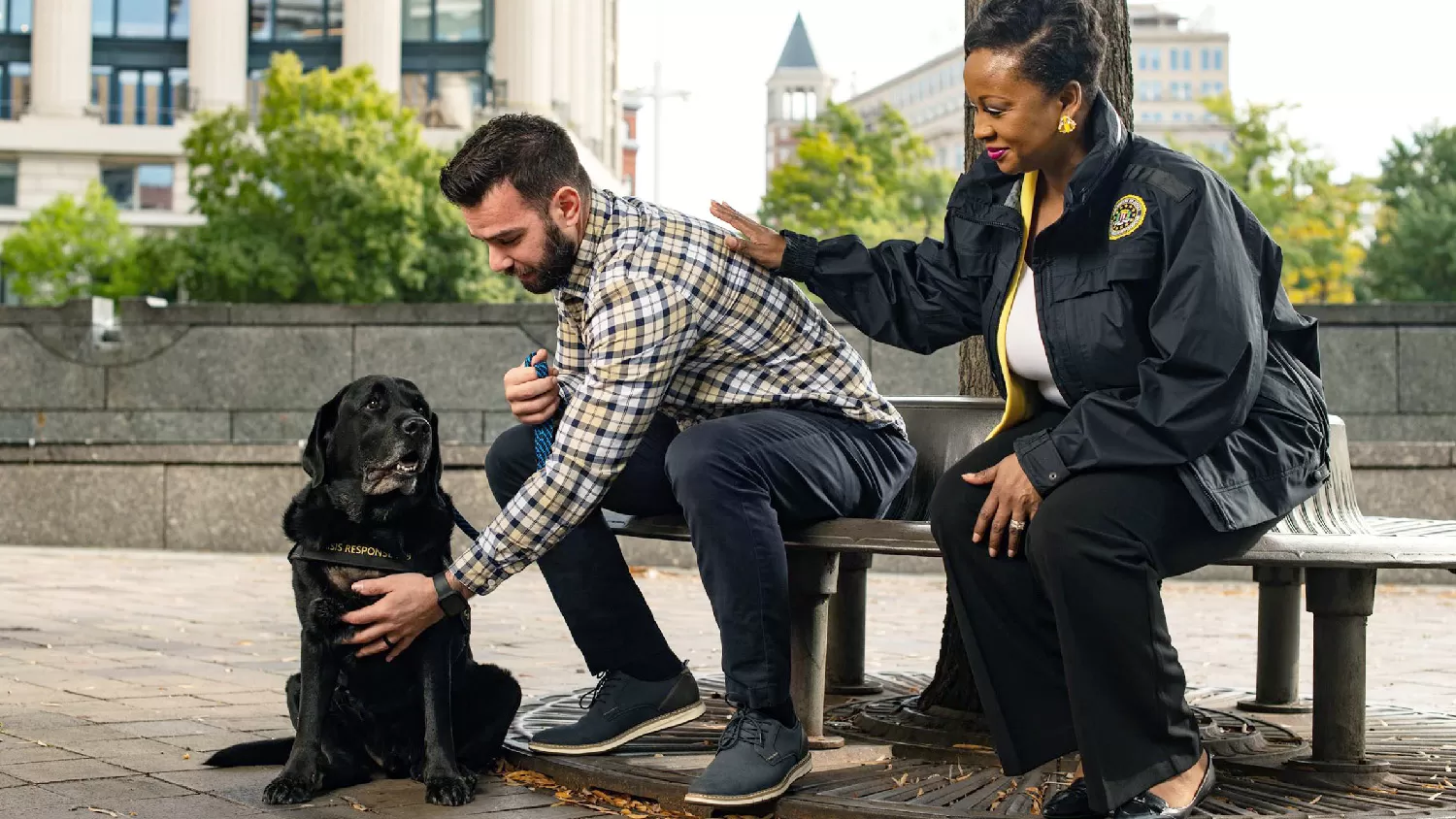Female FBI employee consoling male as he pets FBI dog