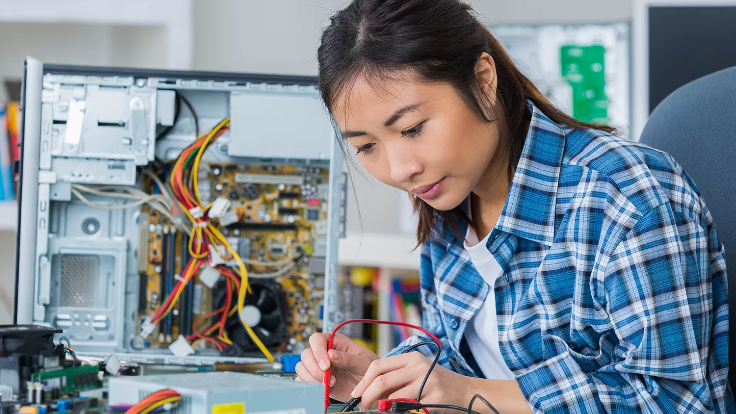 A woman fixing a computer hard drive