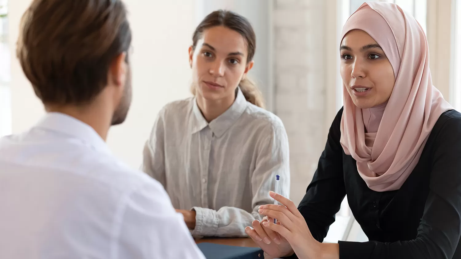 Two women interviewing a man