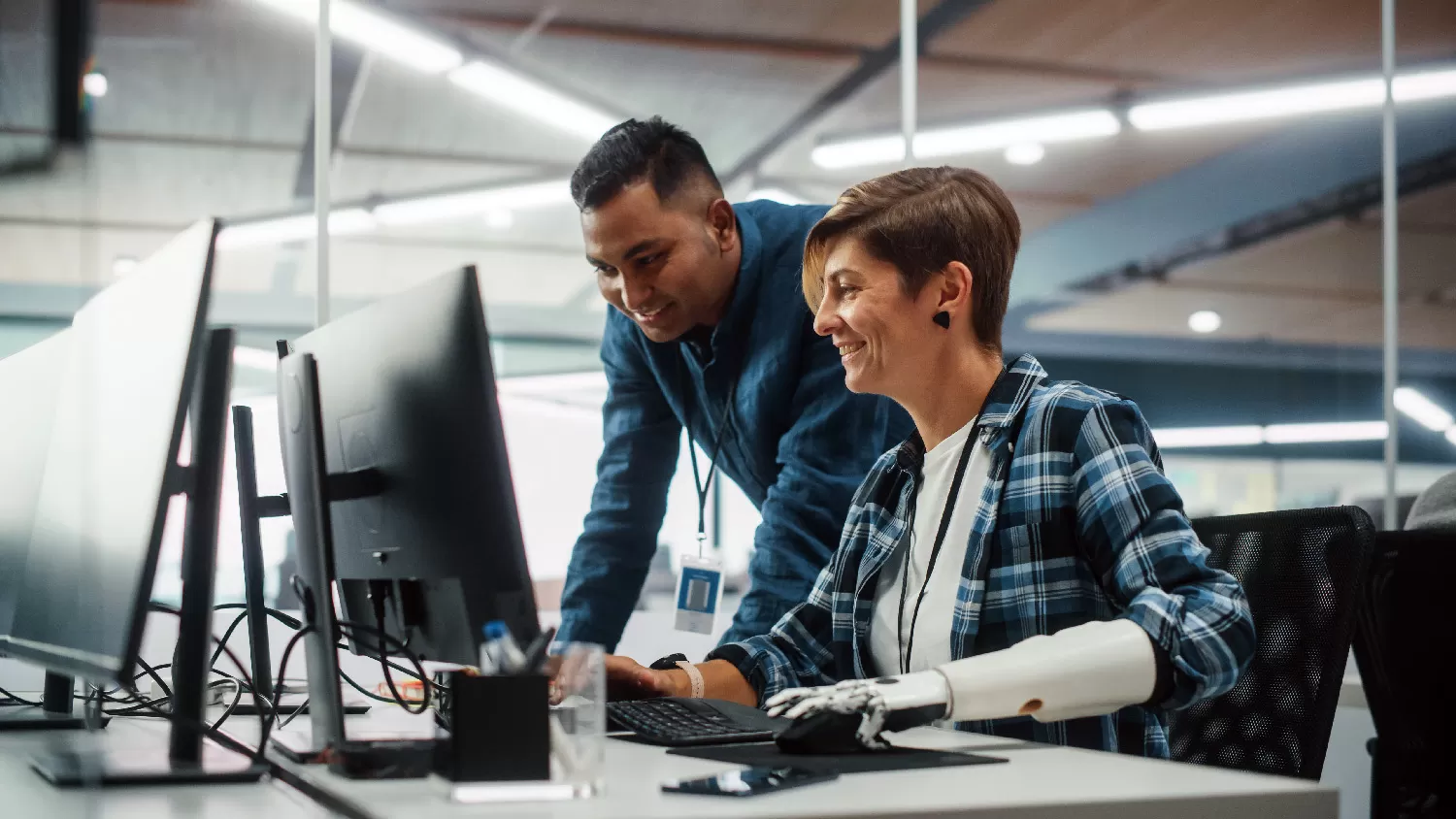 A man and a woman with a prosthetic arm working at a computer