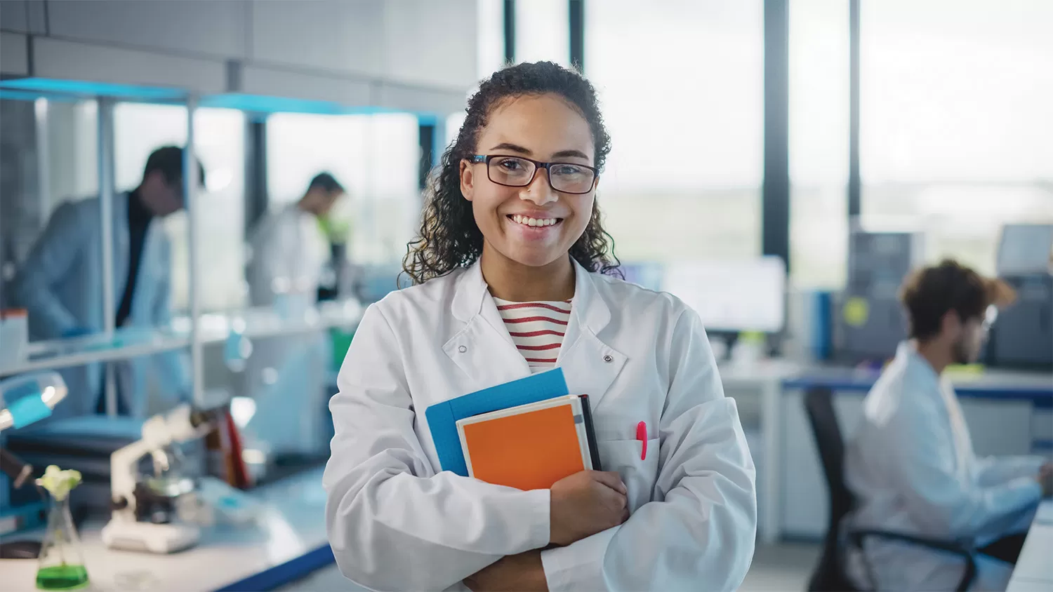 A female student in a lab coat smiling at the camera