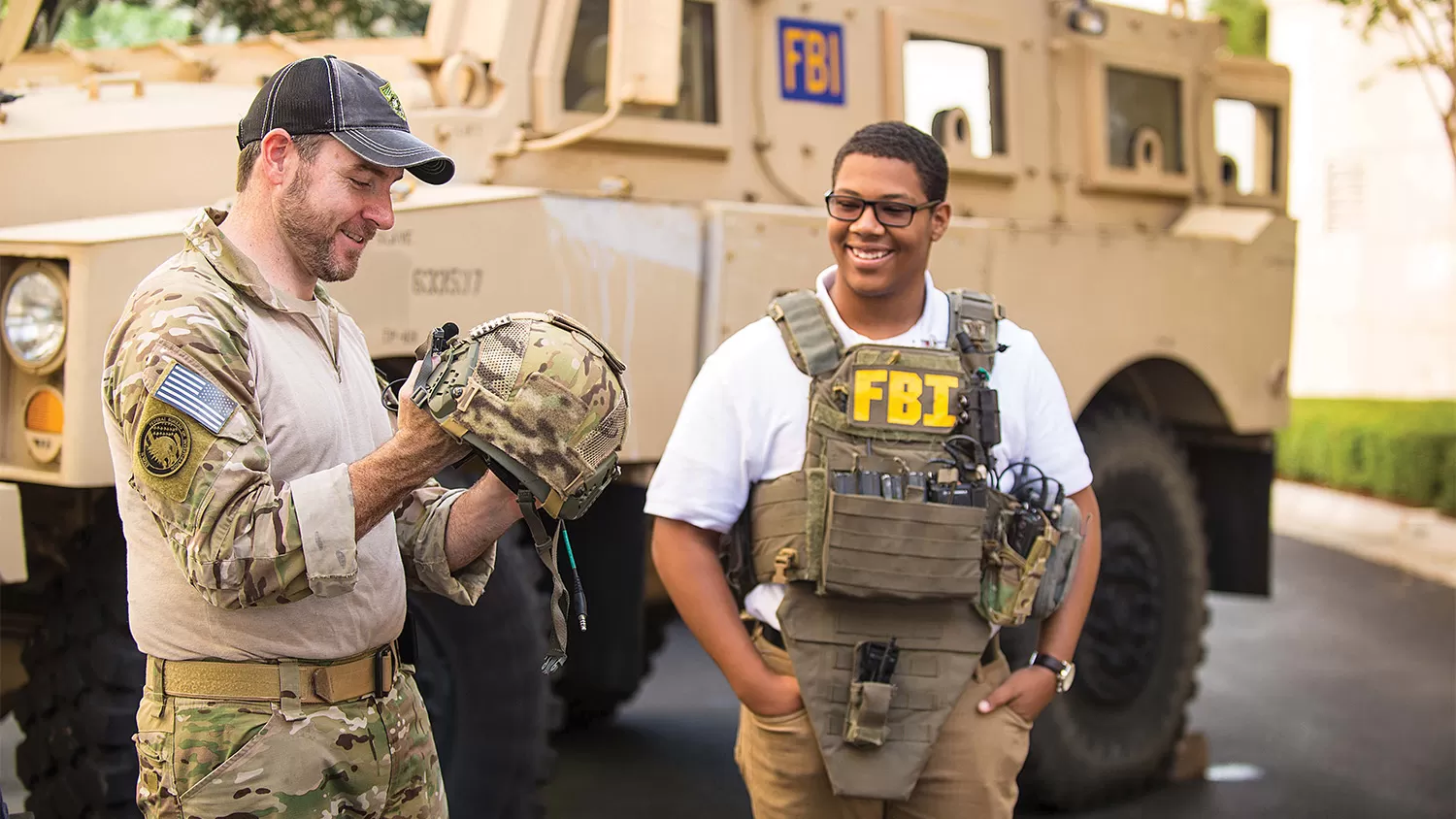 An intern in SWAT gear talking to an FBI employee