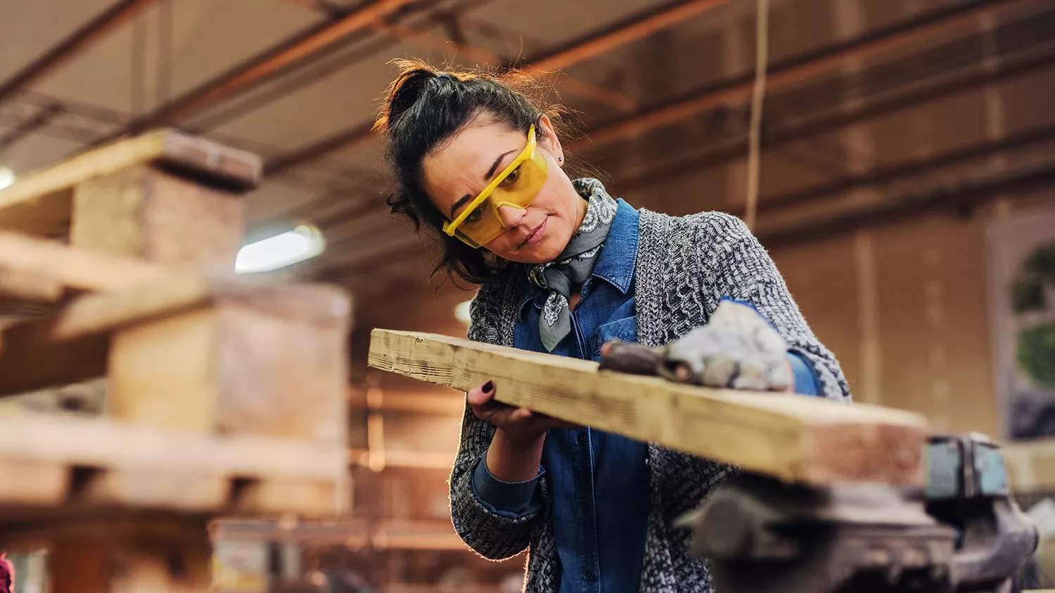 A woman cutting wood in a workshop