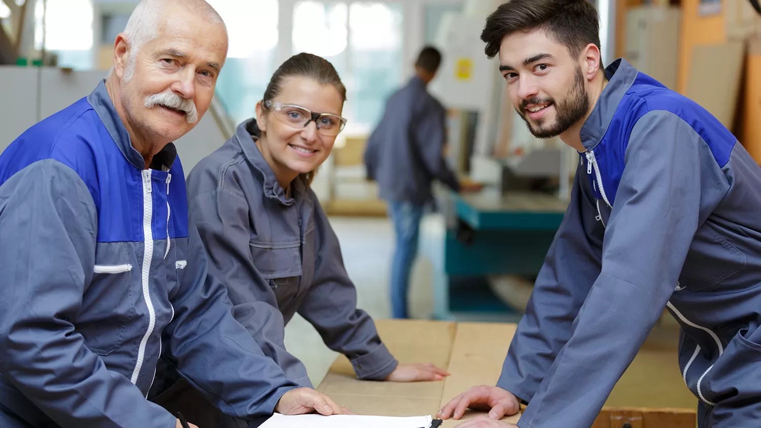 Three people in a workshop smiling at the camera