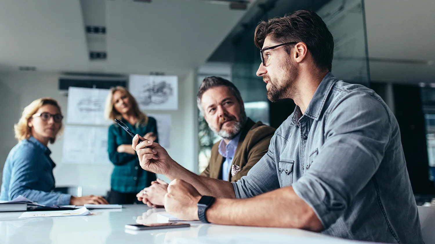 A group of people talking around a table in front of a board