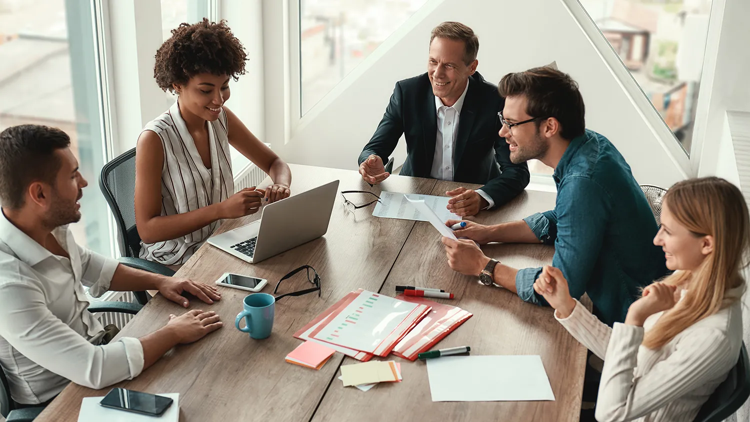 A group of people sitting and talking around a table with papers on it