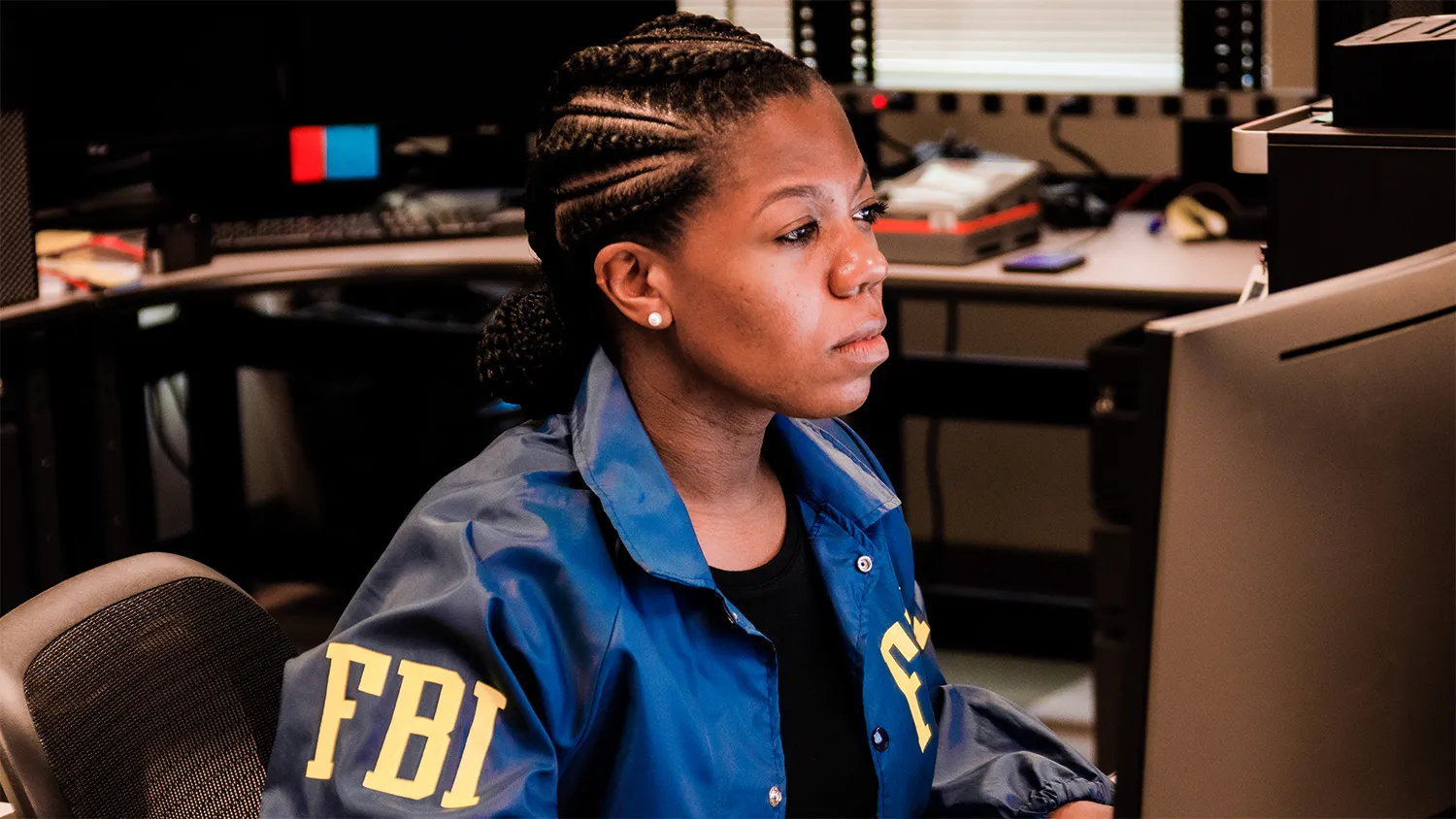 Woman in FBI jacket working at computer