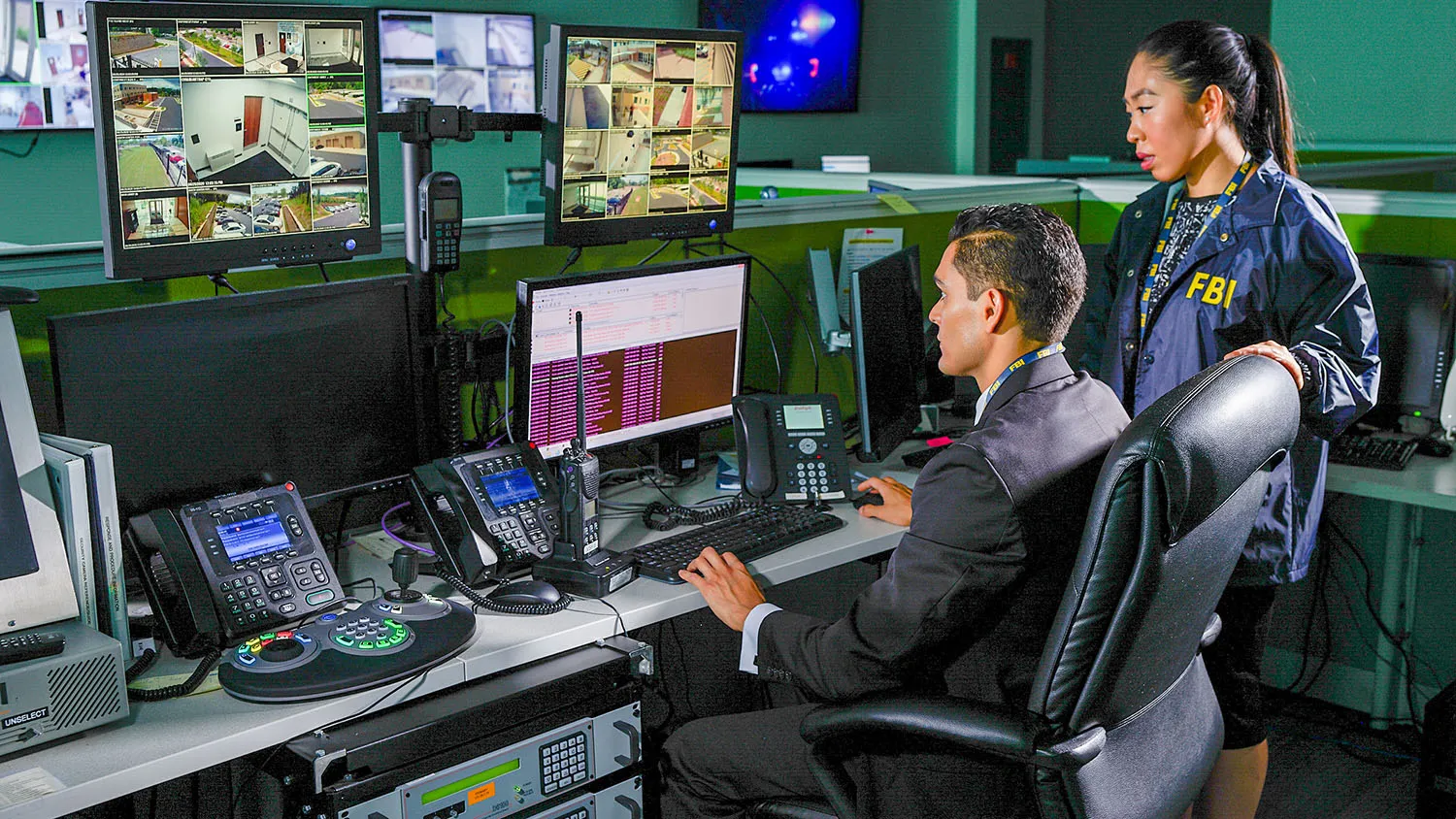 Two FBI employees looking at computer monitors