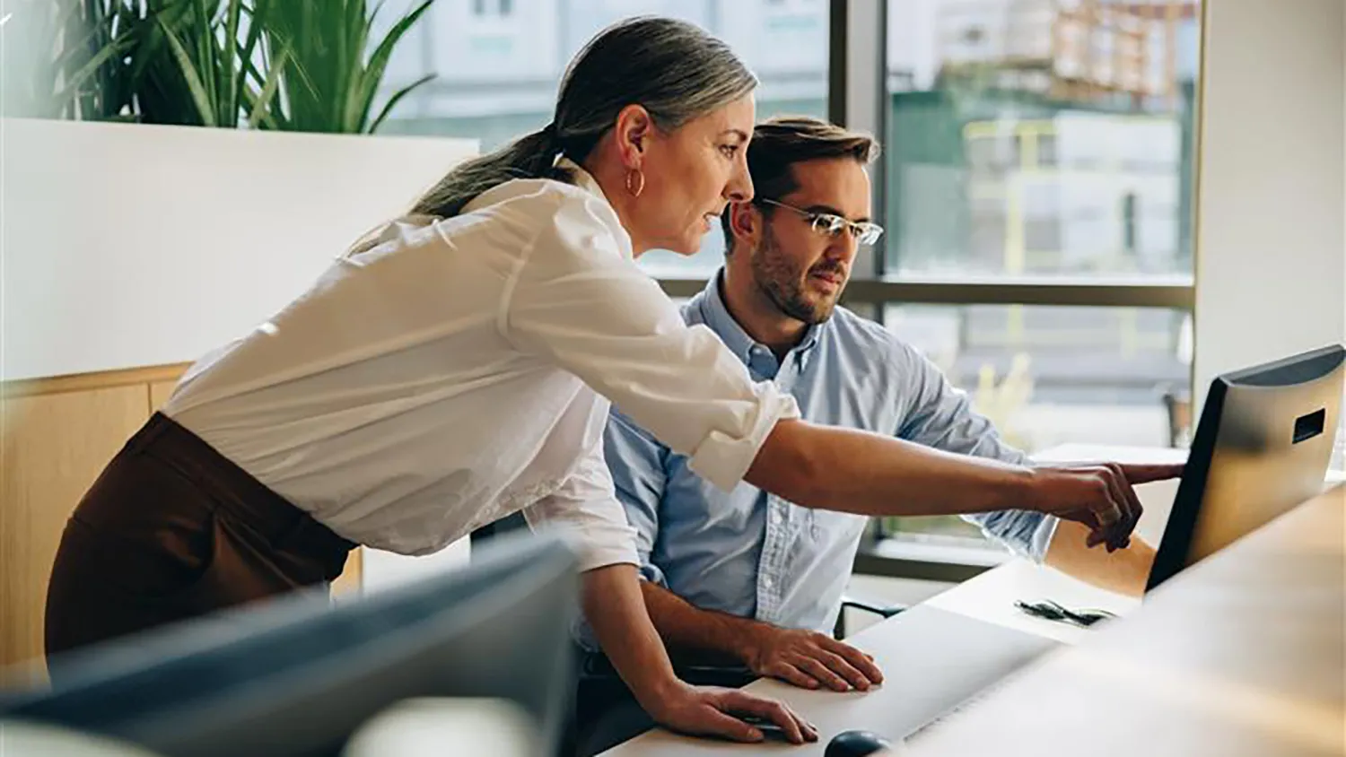 Colleagues looking at and pointing at computer screen. 